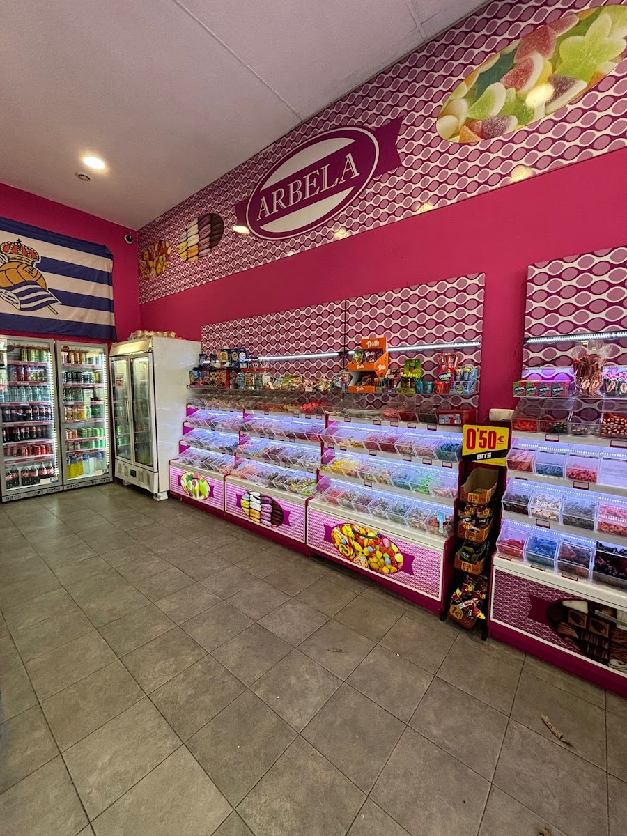 Interior de la tienda: cubetas de golosinas a granel y neveras con refrescos